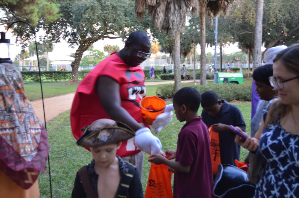 Man dressed as red M&M hands candy to kids
